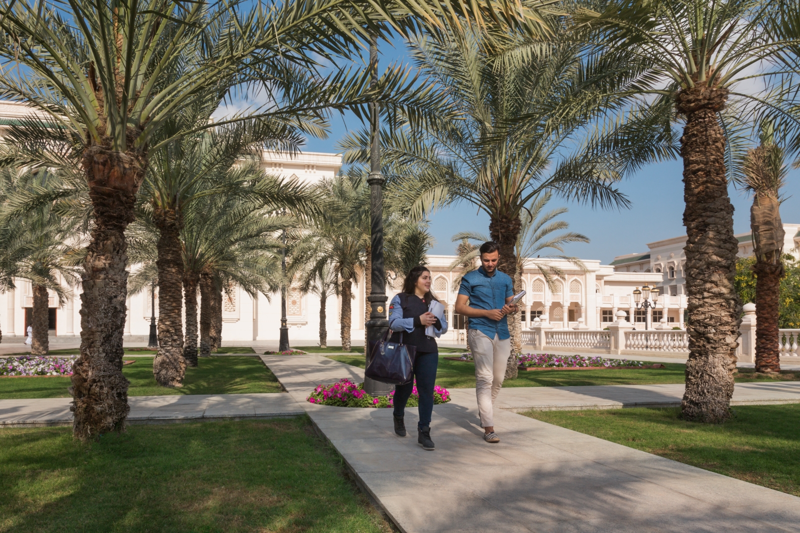 Students walking through the palm-lined campus gardens